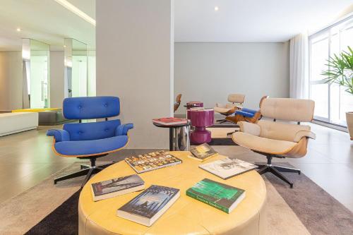 a room with chairs and a table with books at Vossa Bossa VN Turiassu in São Paulo