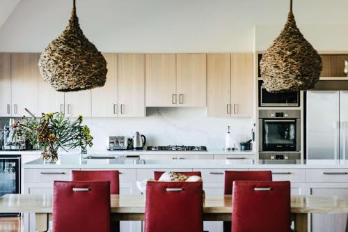 a kitchen with a wooden table and red chairs at Ocean Farm in Gerringong
