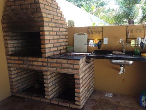 a brick fireplace in a kitchen with a sink at Aconchego da Nina in Jijoca de Jericoacoara