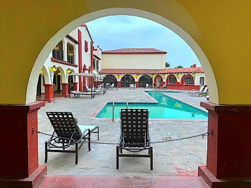 einen Torbogen mit 2 Stühlen und einem Pool in der Unterkunft MISION SANTA ISABEL in Ensenada