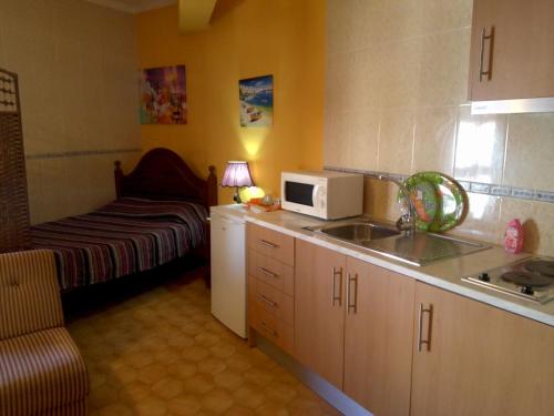 a small kitchen with a sink and a microwave at Guest House Pacifica in Quarteira