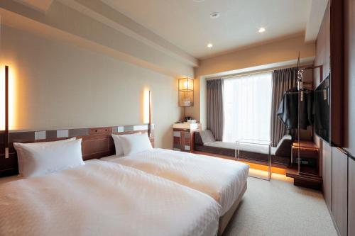 a hotel room with a large bed and a window at Candeo Hotels Kyoto Karasuma Rokkaku in Kyoto