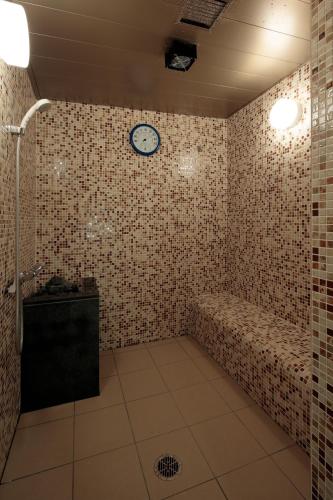 a bathroom with a shower and a clock on the wall at Candeo Hotels Kyoto Karasuma Rokkaku in Kyoto