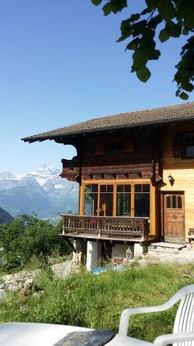 a wooden house on a hill with mountains in the background at Magnifique Chalet Valérie 5 chambres à coucher & vue unique in Gryon