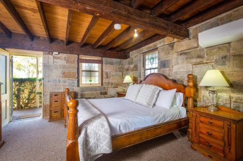 1 dormitorio con cama y pared de piedra en Bimbadeen Mountain House en Mount View