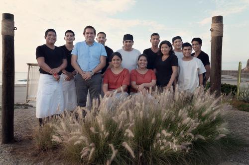 a group of people posing for a picture on the beach at Norte Suites Boutique in Los Órganos