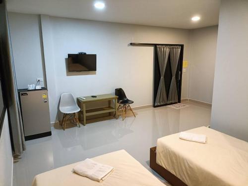 a room with two beds and a desk and a television at Numhom Resort in Ban Nong Chum Saeng