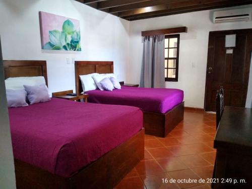 - 2 lits dans une chambre avec des draps violets dans l'établissement MISION SANTA ISABEL, à Ensenada