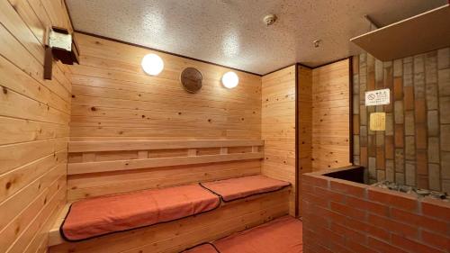 a wooden sauna with a bench in the corner at Spa&Capsule Hotel Grandpark Inn Kitasenju in Tokyo
