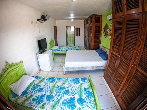 a bedroom with two beds and a tv in it at Hostel e Pousada Bahia Beach in Itanhaém