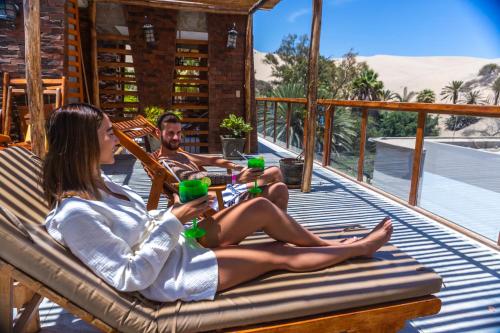 two people sitting on a hammock with green cups at Banana's Adventure Hostel in Ica