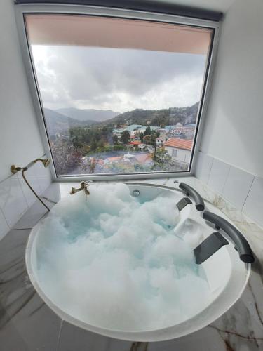 a bath tub in a room with a large window at Aprosmeno Jacuzzi House 1 in Agros