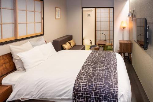 a hotel room with a large bed and a chair at Little Hotel Kyoto Karasuma Takatsuji in Kyoto