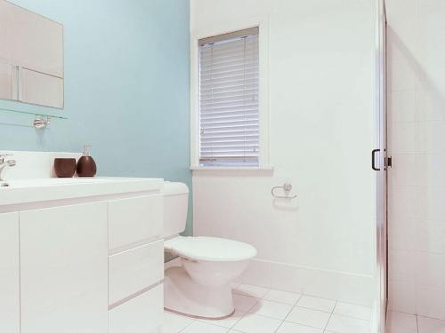 a white bathroom with a toilet and a sink at Ocean Blue Apartment One in Currarong