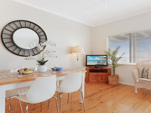 a dining room with a table and white chairs at Ocean Blue Apartment One in Currarong