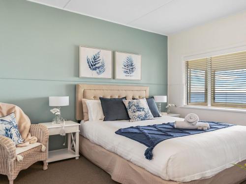 ein Schlafzimmer mit einem großen Bett und einem Stuhl in der Unterkunft Ocean Blue Apartment Two in Currarong