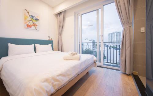 een slaapkamer met een bed en een groot raam bij ICASA Serviced Apartment in Ho Chi Minh-stad