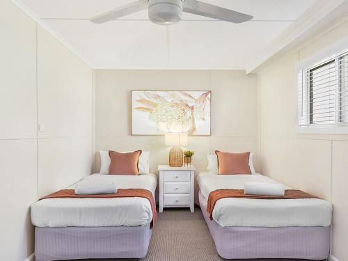 two beds in a bedroom with white walls and a ceiling at Ocean Blue Apartment Five in Currarong