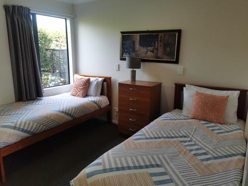 a bedroom with two beds and a window and a dresser at ASURE Ascot Motor Inn in Taupo