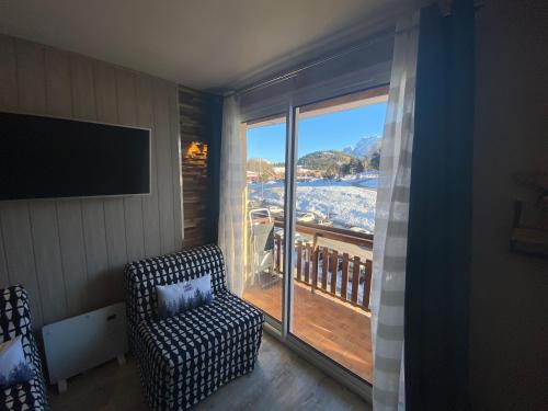 a living room with a chair and a large window at STUDIO COCOONING SUPERDEVOLUY PIED DES PISTES in Le Dévoluy