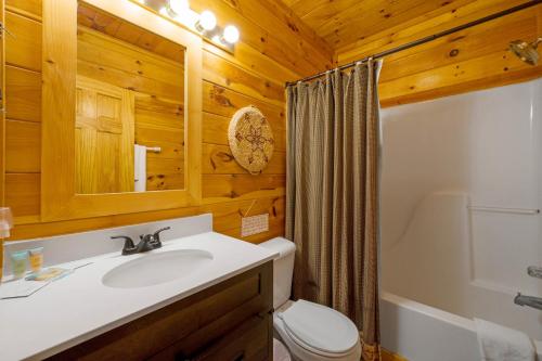 a bathroom with a sink and a toilet and a mirror at Peaks of Blue with Hot Tub and Theater Room in Sevierville