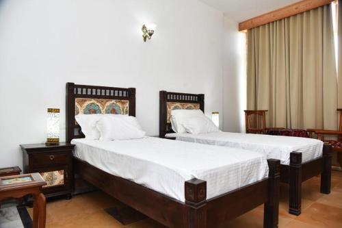 - une chambre avec 2 lits et des draps blancs dans l'établissement Osian The Desert Boutique Hotel, à Khāra