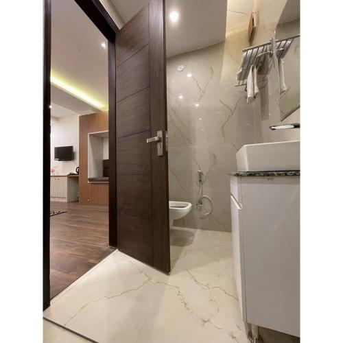 a bathroom with a toilet and a wooden door at Maps Inn in Ghaziabad