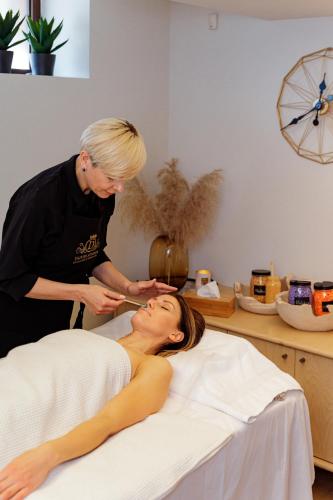 a woman laying on a bed with a therapist at Kerpė Hotel & SPA in Palanga