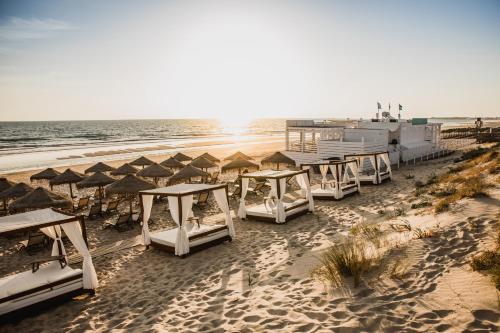 
a beach area with chairs, tables, and boats at Gran Meliá Sancti Petri in Chiclana de la Frontera
