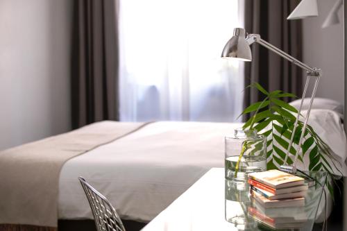 a table with a plant and a lamp and a bed at N - SPACE modern guestrooms in Rome