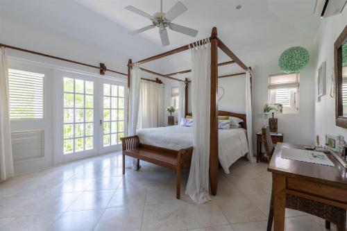 a bedroom with a canopy bed and a sink at Shimmers, stunning, stylish West Coast Villa in Saint Peter
