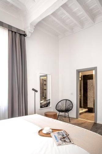a white bedroom with a bed and a chair at N - SPACE modern guestrooms in Rome