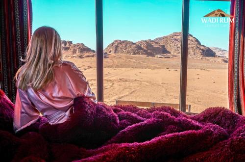 Una mujer sentada en un autobús mirando por la ventana del desierto en Wadi Rum Starlight Camp en Wadi Rum