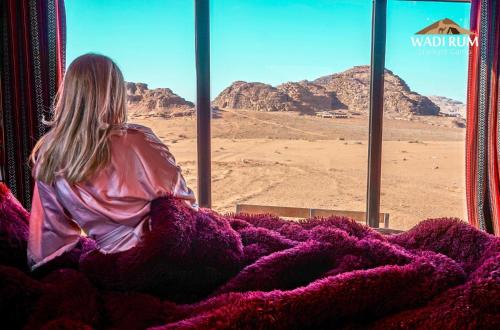 a woman sitting on a bus looking out a window at the desert at Wadi Rum Starlight Camp in Wadi Rum