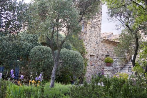 an old stone building with trees and plants at Mas de la Beaume in Gordes