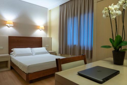 a bedroom with a bed and a table with a laptop on it at Esperia Hotel in Kavala