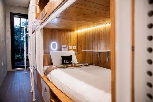 a bedroom with a bed in a room with wooden walls at Tuju Arteri Pods in Jakarta