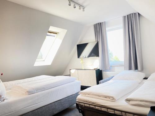 two beds in a room with two windows at Hotel Xenia Flensburg in Flensburg