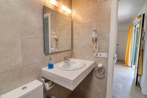 un baño con lavabo y espejo en Apartamentos Las Golondrinas, en Cala'n Bosch