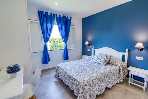 een blauwe slaapkamer met een bed en een raam bij Apartamentos Las Golondrinas in Cala'n Bosch