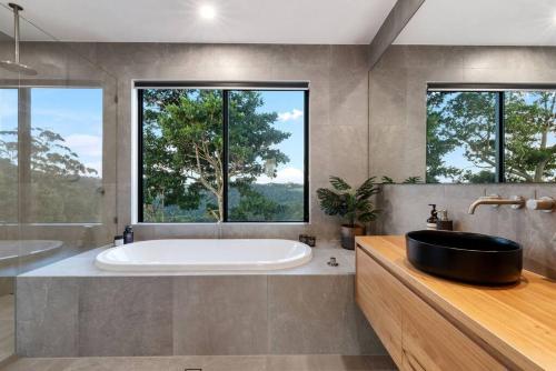 a bathroom with a tub and a sink and two windows at The Ridge at Maleny 3 Bedroom Executive Residence in Maleny
