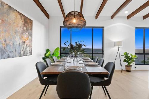 a dining room with a table and chairs and windows at The Ridge at Maleny 3 Bedroom Executive Residence in Maleny