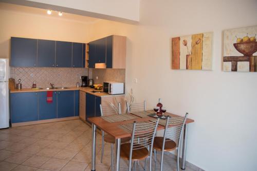 a kitchen with blue cabinets and a wooden table and chairs at Spira Studios & Apartments in the Heart of Laganas in Laganas