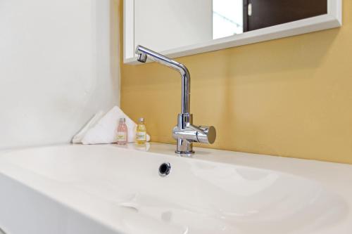 een wastafel in de badkamer met een kraan en een spiegel bij Rincon Plaza Hotel in Rincon