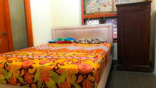 a bedroom with a bed with a colorful blanket at Losmen 2000 Tiga in Yogyakarta