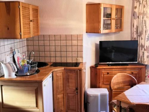 una cocina con armarios de madera y TV en una encimera en Bungalow Poggendorf en Eldena