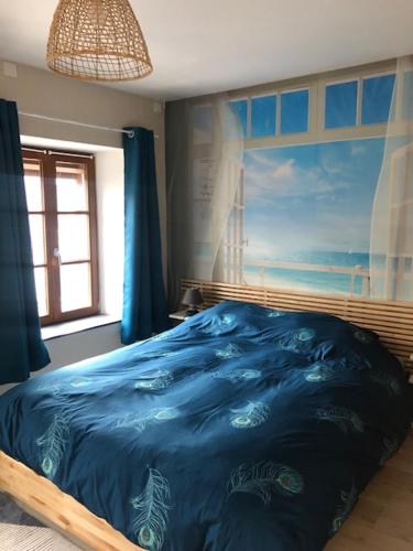 - une chambre dotée d'un lit bleu et d'une peinture murale dans l'établissement Les Aubennes, à Fromelennes