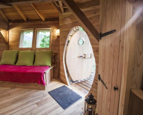 Cette chambre en bois comprend un lit et un grand miroir. dans l'établissement Gaïa - Les Cabanes du Chêne Rouvre, à Saint-Dié-des-Vosges