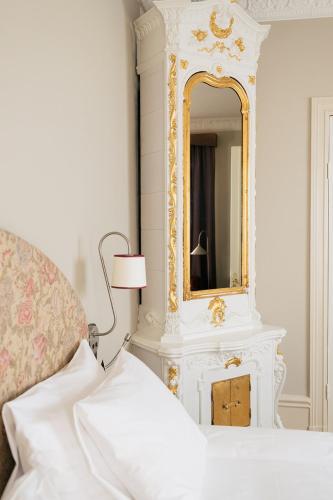 a white bedroom with a mirror and a bed at Hotel Ruth, WorldHotels Crafted in Stockholm