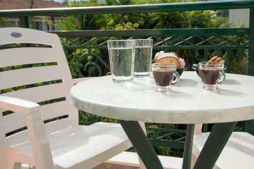 a white table with two glasses and a pastry on it at Spira Studios & Apartments in the Heart of Laganas in Laganas